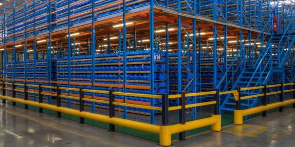 cropped-J2P9284_85_86_87_88_89_90-scaled-1.jpg Interior of a large warehouse showing extensive bolted shelving blue rack-supported mezzanine floors filled with organized shelves, under a high ceiling with industrial lighting