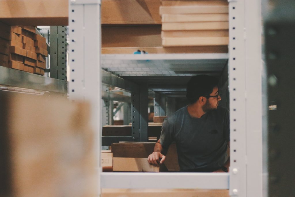 man handling boxes between warehouse shelving