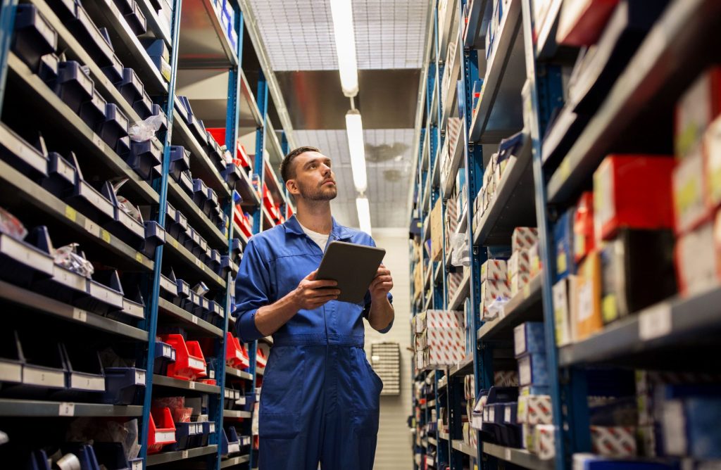 Car mechanic standard amid bolted shelving in a warehouse