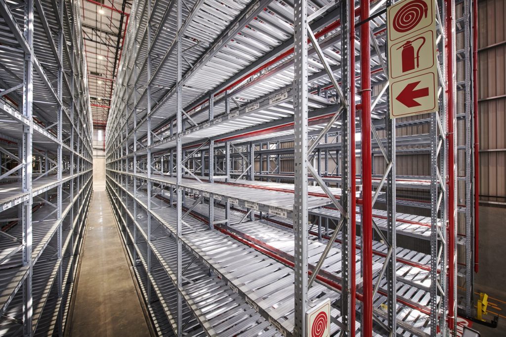 Row of heavy duty metal shelves in a warehouse with warning signs