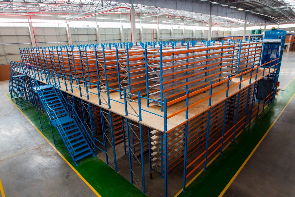 Mezzanine floor with orange and blue shelving units in an industrial warehouse