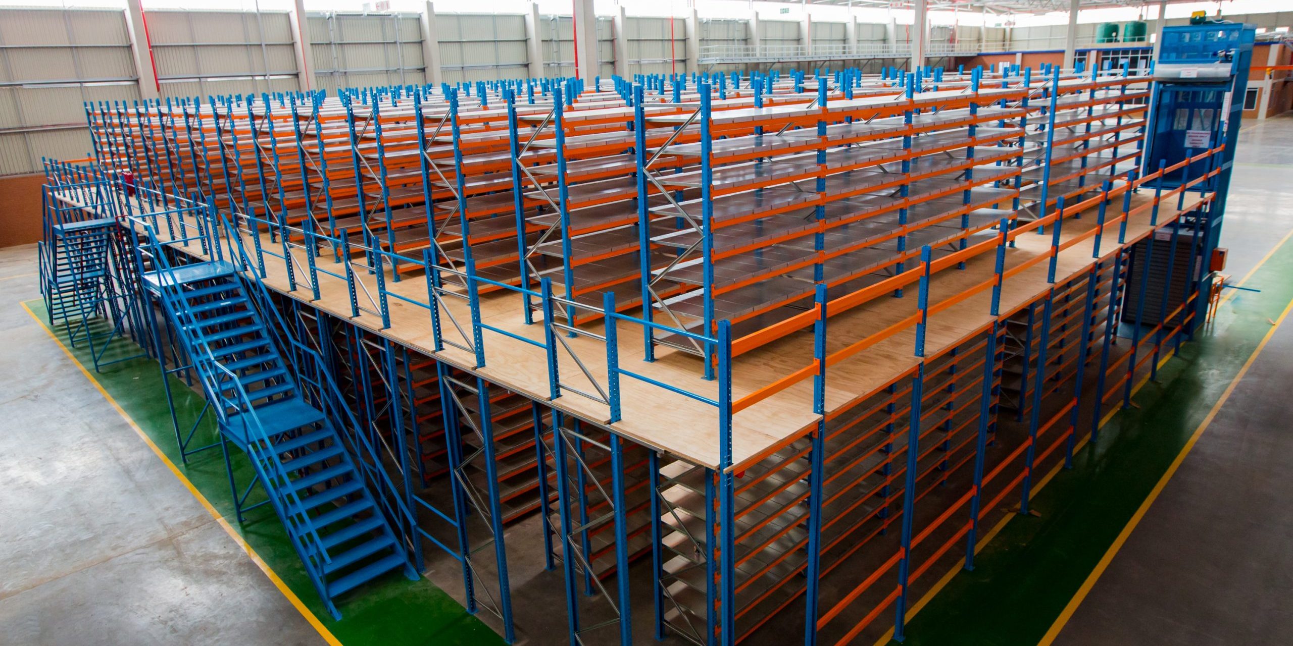 Krost-107 (1) Mezzanine floor with orange and blue shelving units in an industrial warehouse