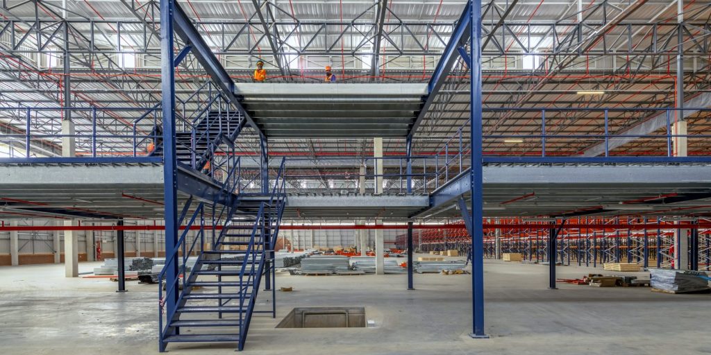 People on a structural mezzanine floor installation in a warehouse. Looking for structural mezzanine prices