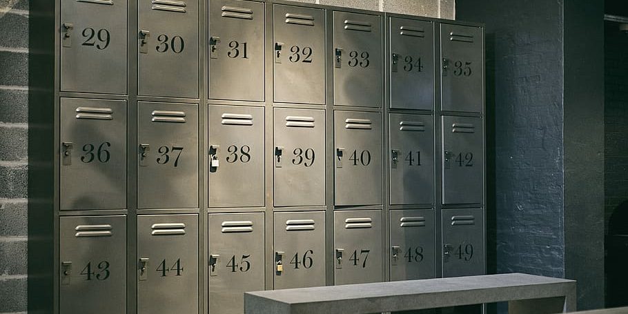 cabinet-locker-locker-room-numbers Row of steel lockers prices numbered 29 to 49 in a dimly lit room, providing secure storage solutions for businesses or facilities.