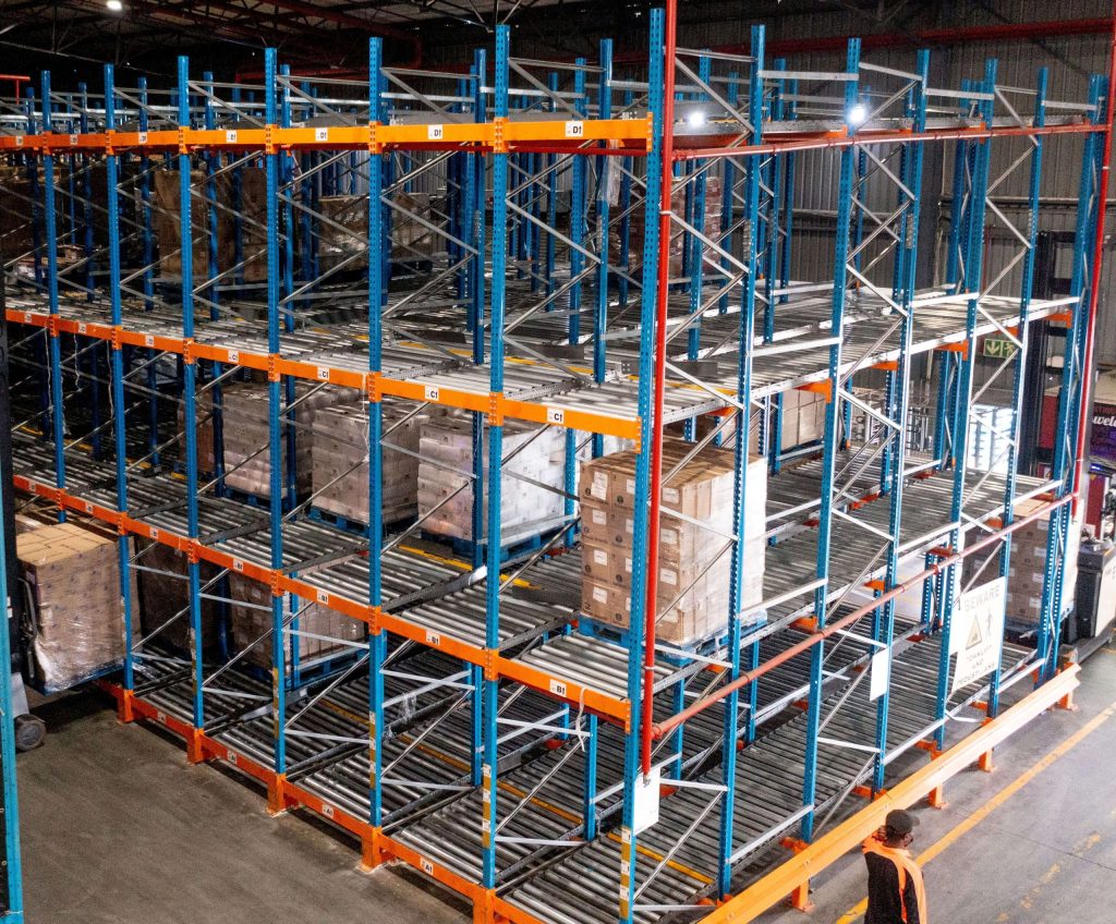 A tall blue and orange structure in a warehouse serving as a high-density storage solution for bulky goods