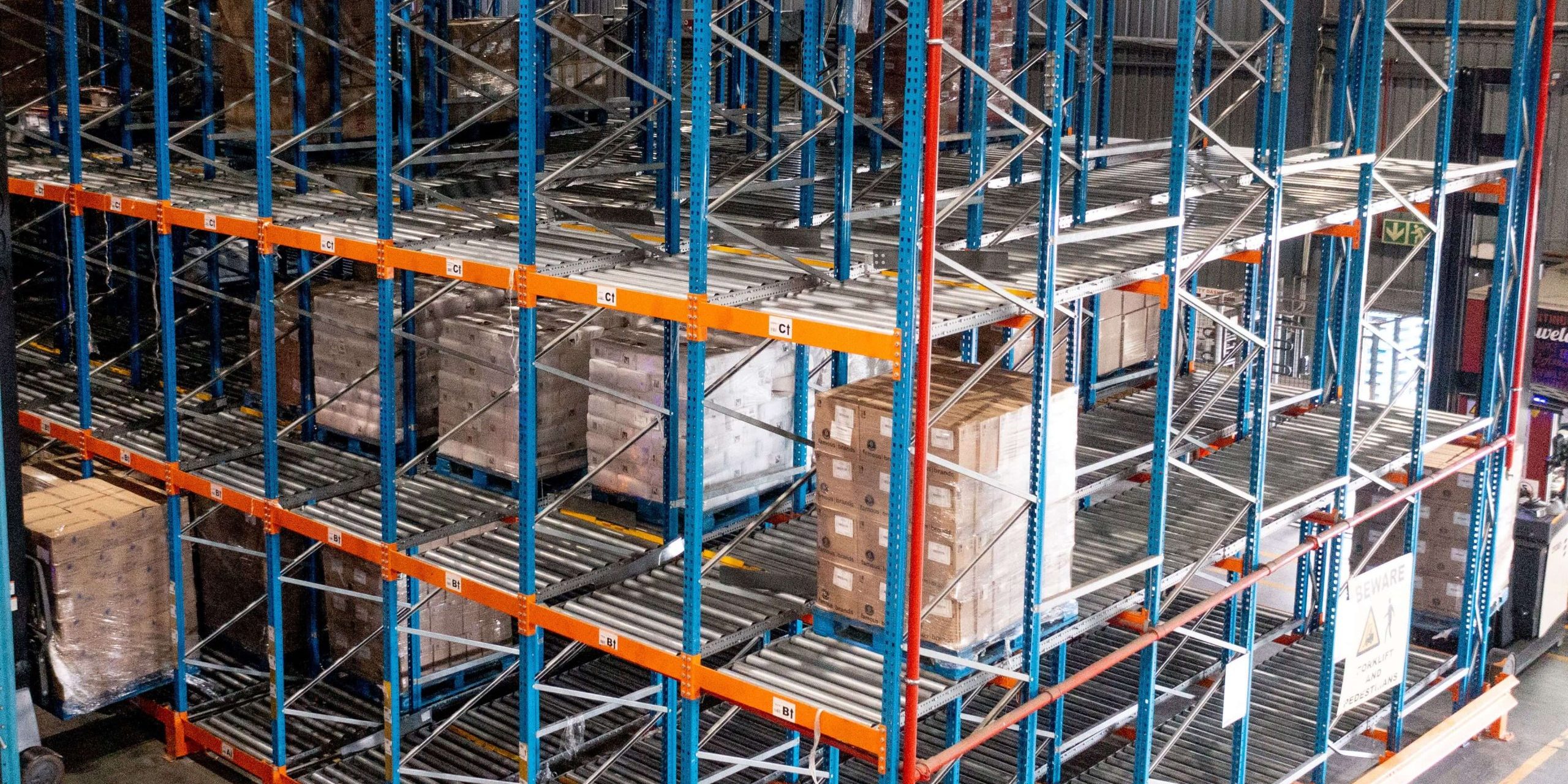 A tall blue and orange structure in a warehouse serving as a high-density storage solution for bulky goods