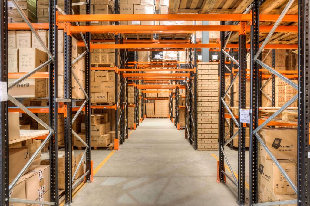 A warehouse interior with tall shelving units stocked with labelled cardboard boxes organised for optimal order fulfilment