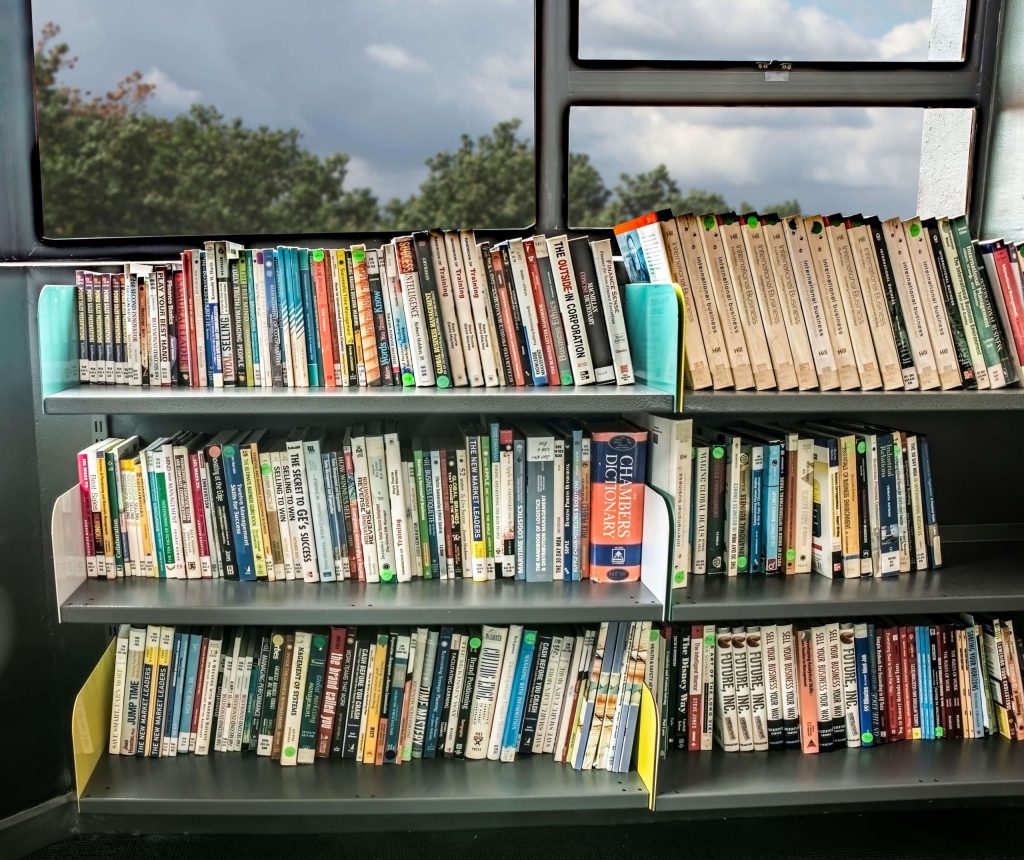 Rivet shelving vs library shelving: metal library shelves mounted under large windows and stacked with educational books
