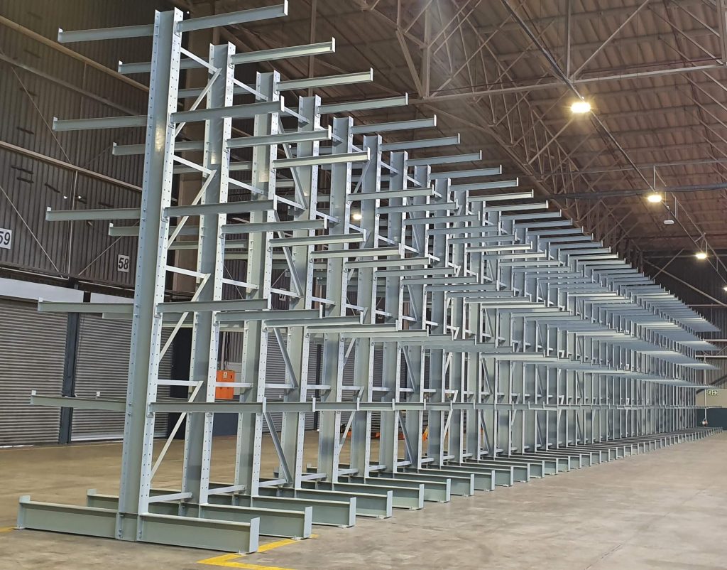 Long row of a grey cantilever racking system in a large empty warehouse, contrasting cantilever racking vs. drive-in-racking
