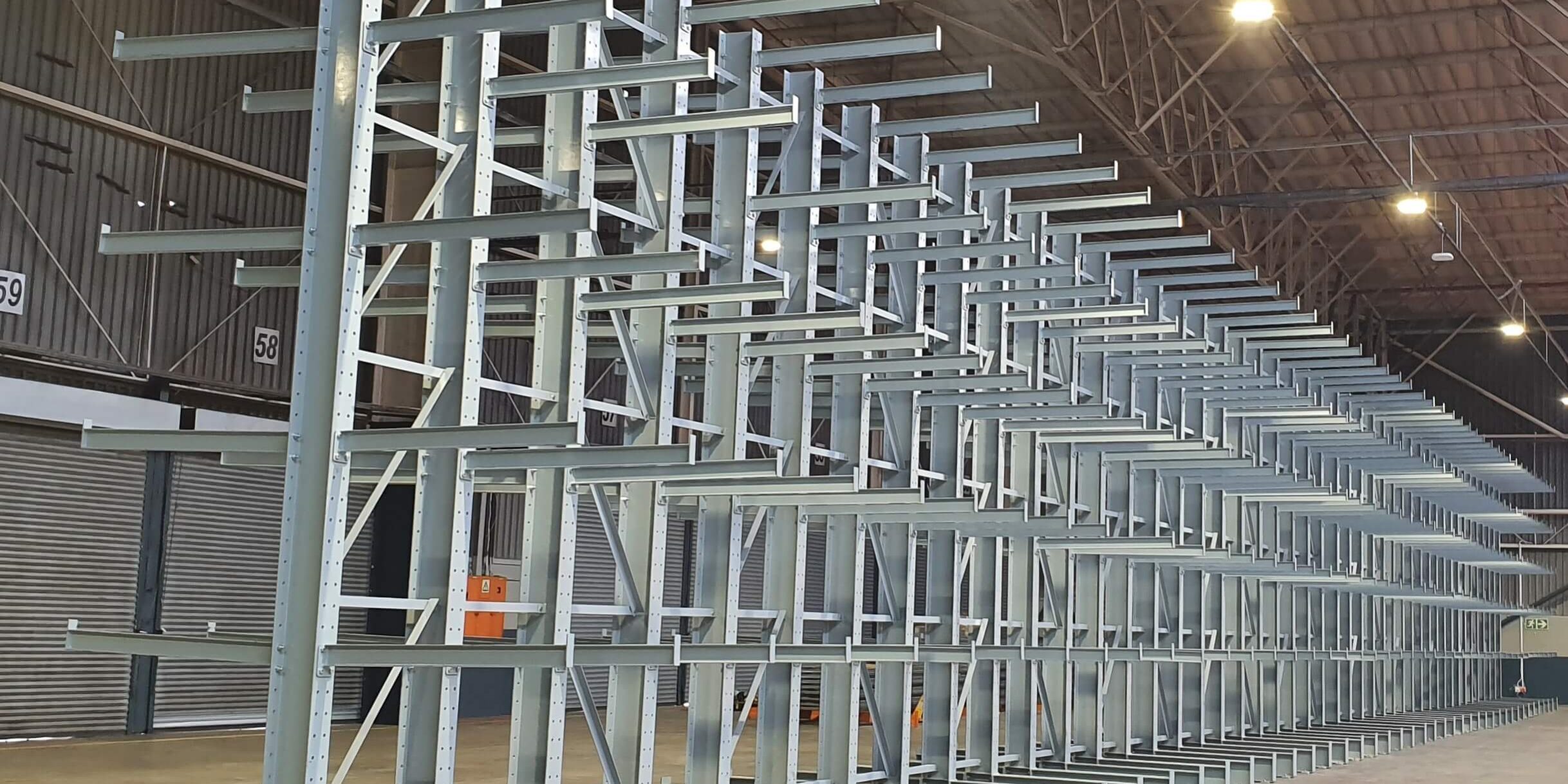 20240130_122233 Long row of a grey cantilever racking system in a large empty warehouse, contrasting cantilever racking vs. drive-in-racking