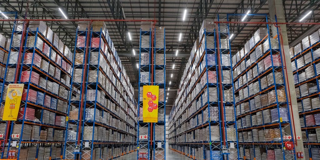 Krost-9 Ceiling high blue and orange pallet racking system stacked with pallets to indicate pallet shuttle system prices