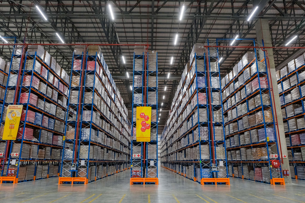 Ceiling high blue and orange pallet racking system stacked with pallets to indicate pallet shuttle system prices