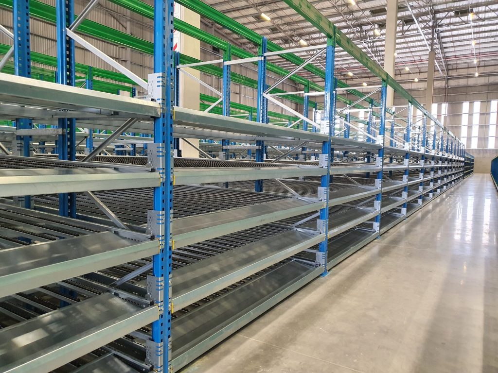 Empty industrial metal shelving units inside a large warehouse with polished concrete floor.