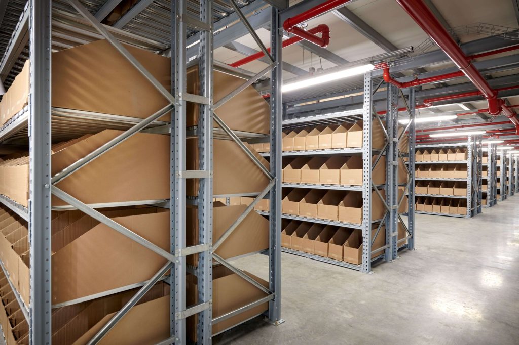 A stock storage area with steel rivet shelving stacked with flattened cardboard boxes
