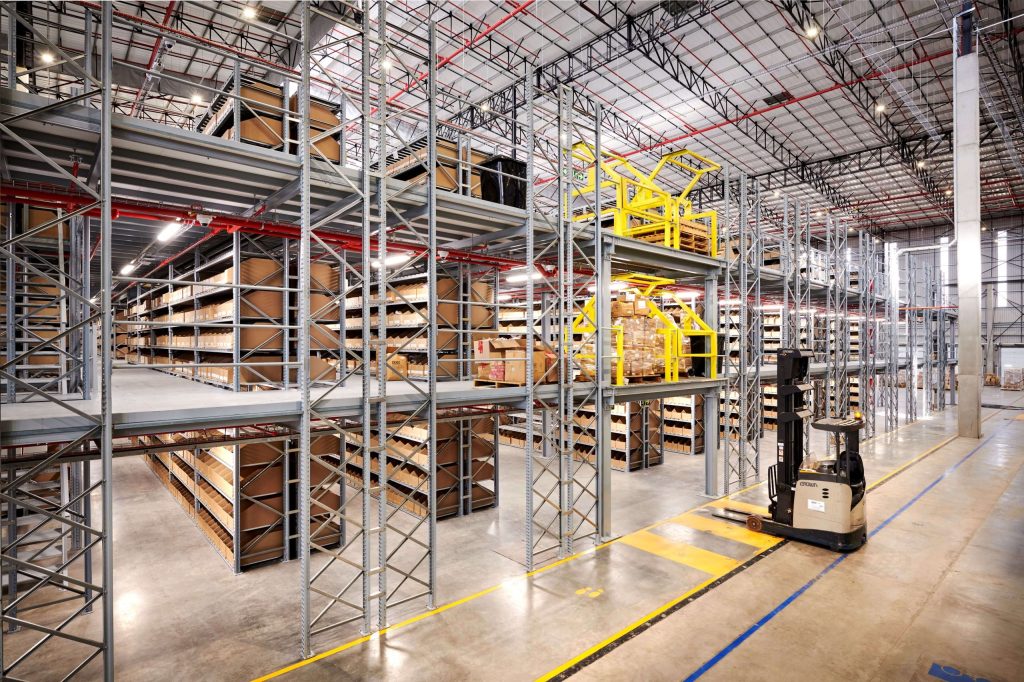 A massive Cotton-On warehouse with tall rivet shelves stacked with boxes and a forklift nearby