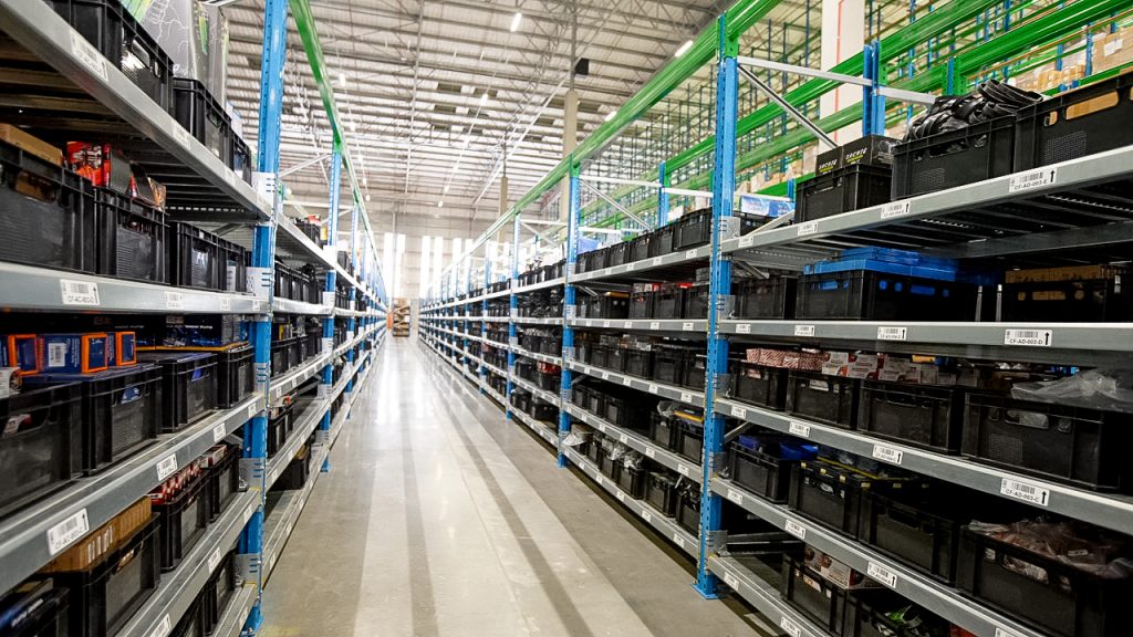 Flow racking system packed with black crates in a warehouse.