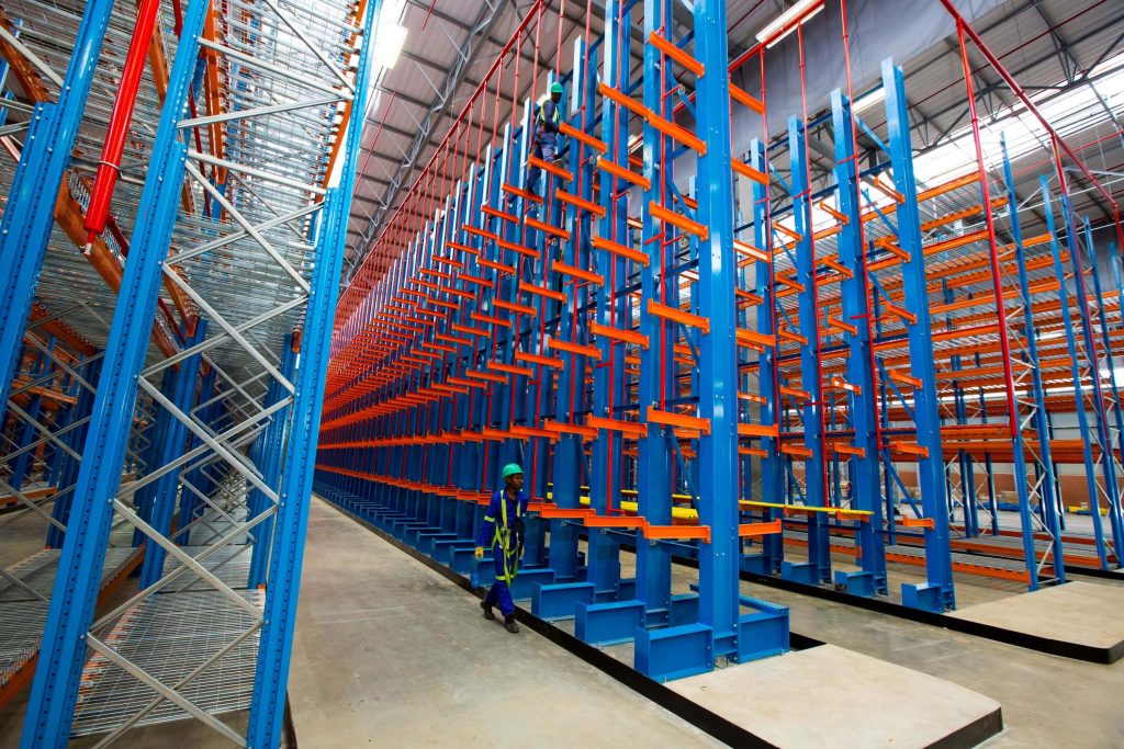 Worker in blue overalls walking beside an empty 6 level cantilever racking structure
