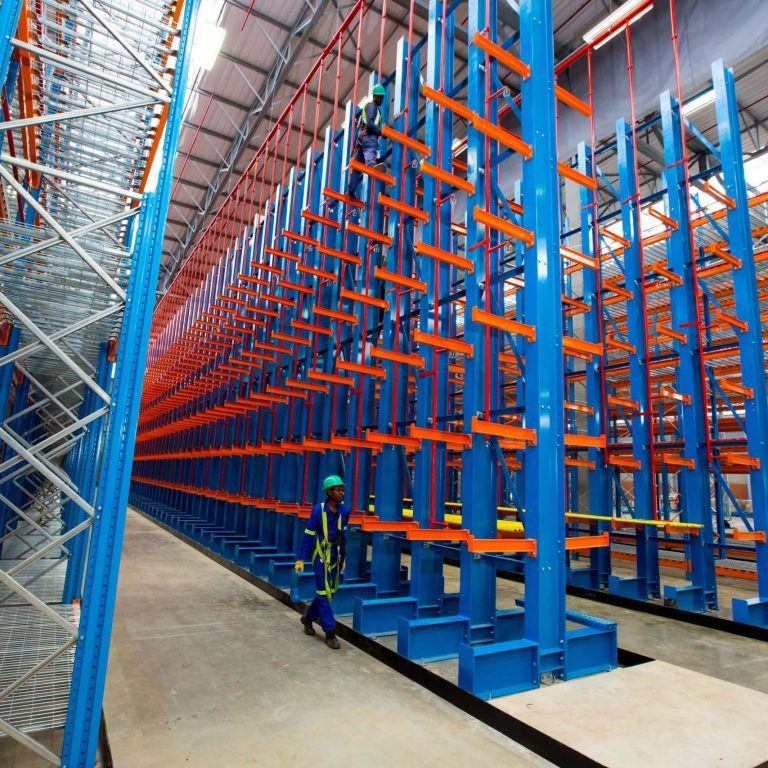 Worker in blue overalls walking beside an empty 6 level cantilever racking structure