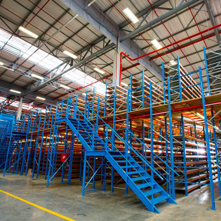Industrial warehouse with blue steel mezzanine floors and shelving system for optimised storage solutions.