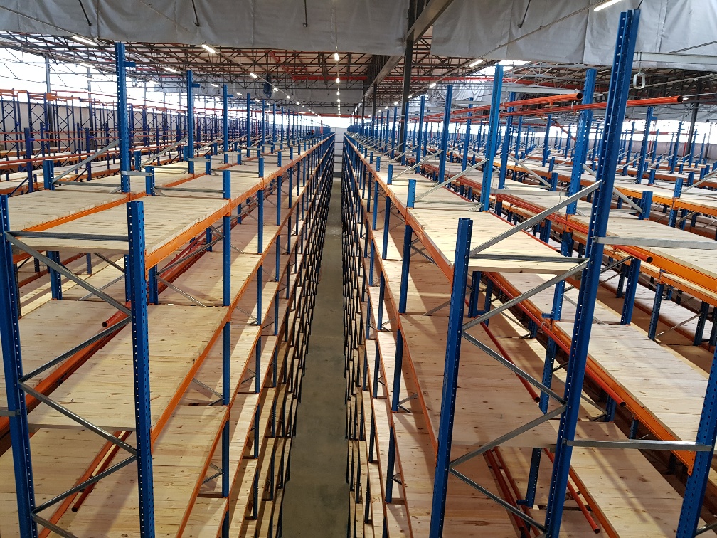 A wide view of a spacious warehouse filled with high metal shelving units, organized for efficient storage and inventory management.