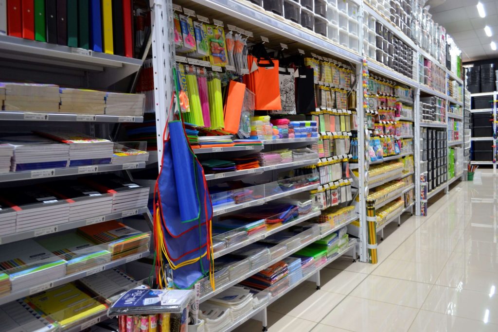 Robust gondola retail shelving options neatly piled with stationery in a supermarket