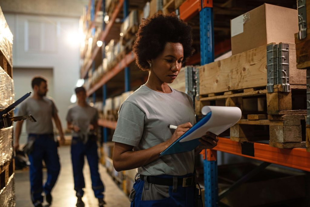 Female worker implementing effective warehouse space optimisation by checking stored items