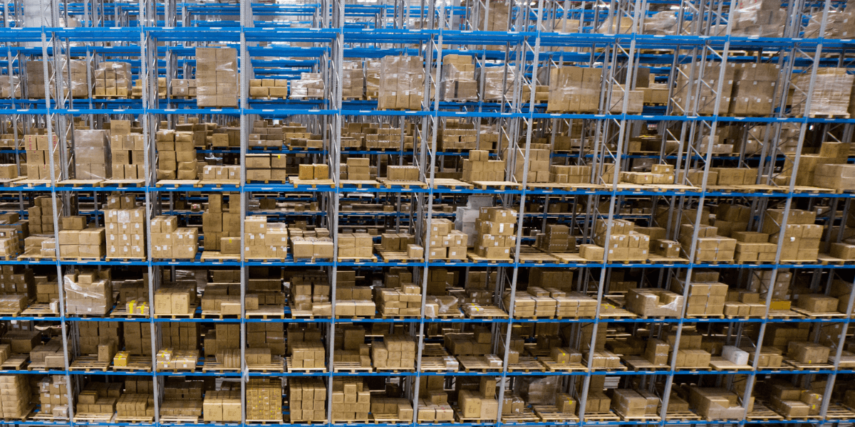 N2GtQ9Rg Warehouse shelves stacked high with numerous brown cardboard boxes organized on blue racks.