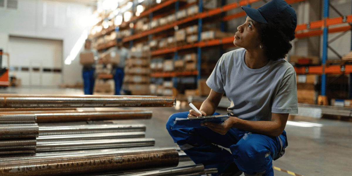 Top Tips for Warehouse Shelving Efficiency Female warehouse worker noting warehouse shelving efficiency on a clipboard.