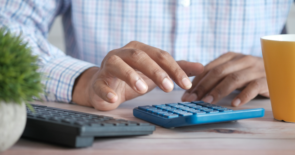 Man using a calculator to workout if warehouse shelving is affordable