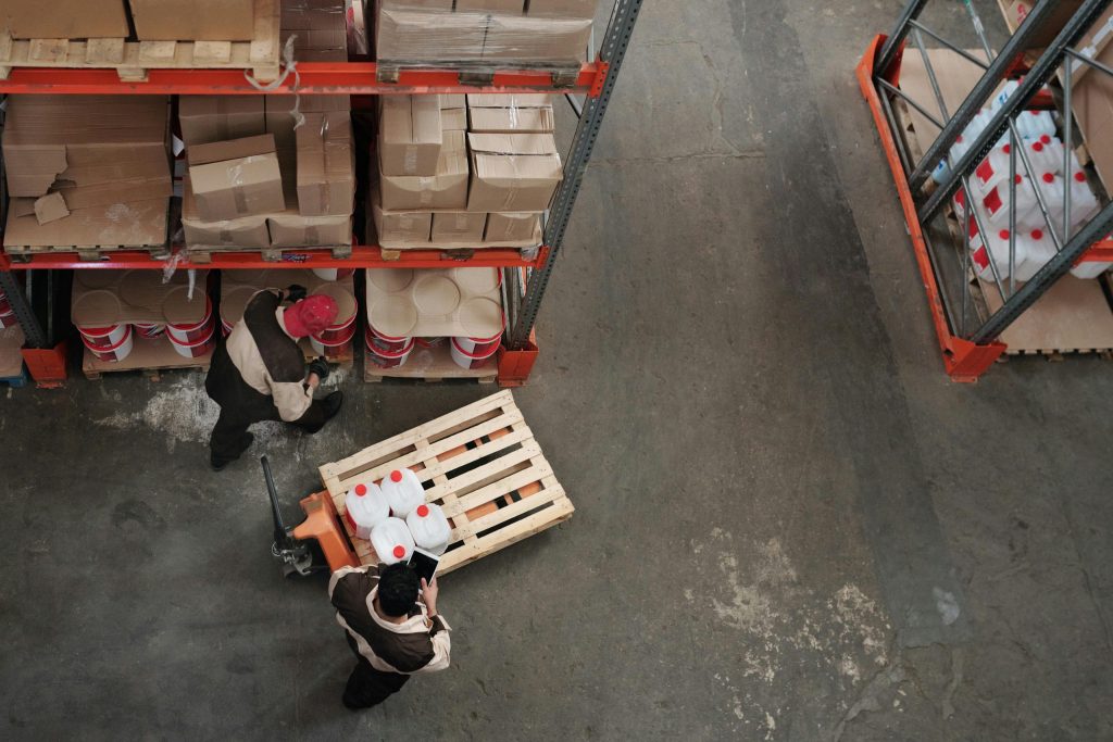 Selective pallet racking vs. bolted shelving: Man in overalls showing colleague number on warehouse rack