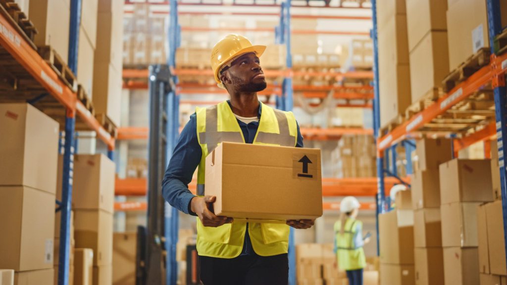 A worker carrying a box in a warehouse using an efficient warehouse dispatch process