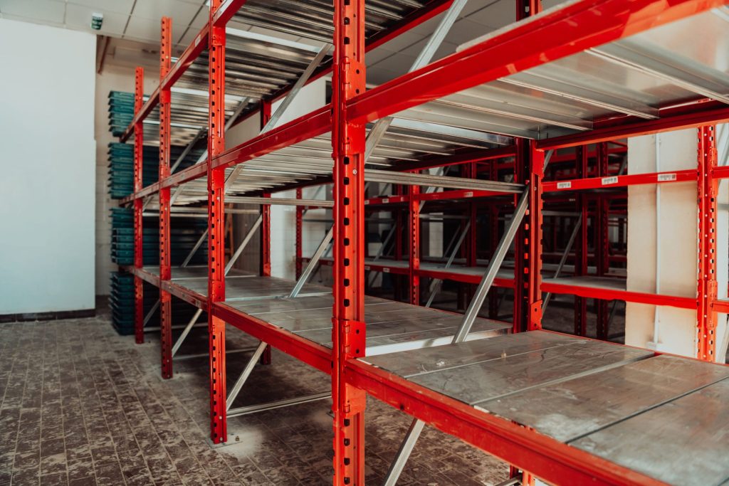 Red industrial racks with metal shelving in a warehouse, showcasing efficient racking solutions for maximising small storage spaces.