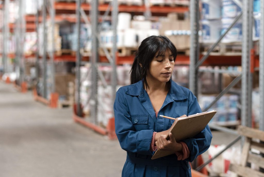 A female worker in a warehouse, calculating the cost of warehouse racking per square foot