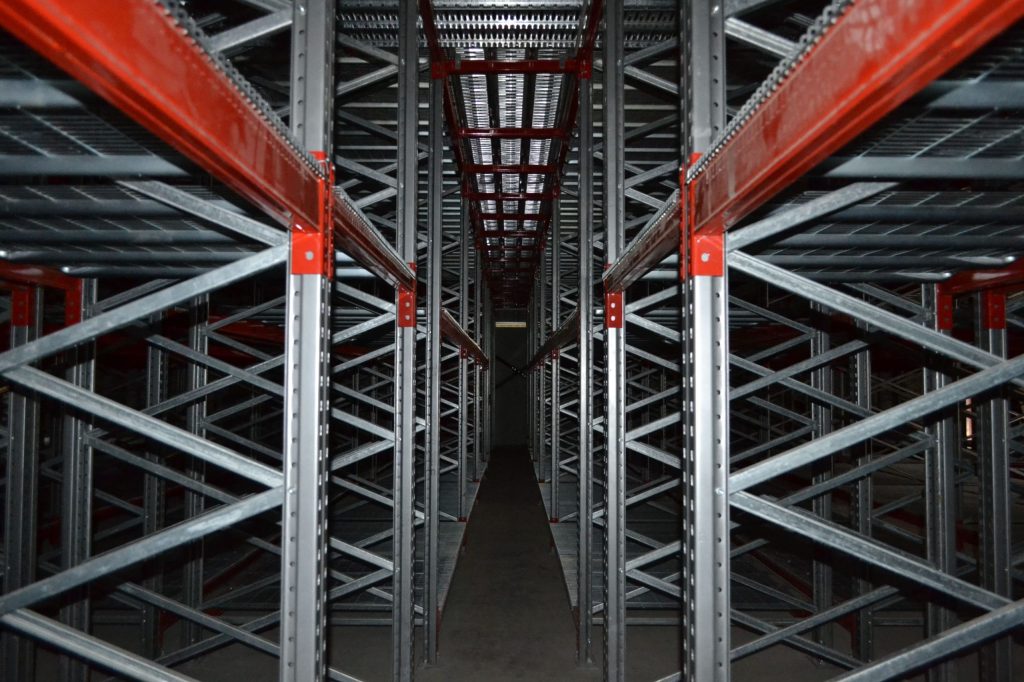 Close up of a catwalk racking floor in a dark warehouse, comparing catwalk racking and rivet shelving