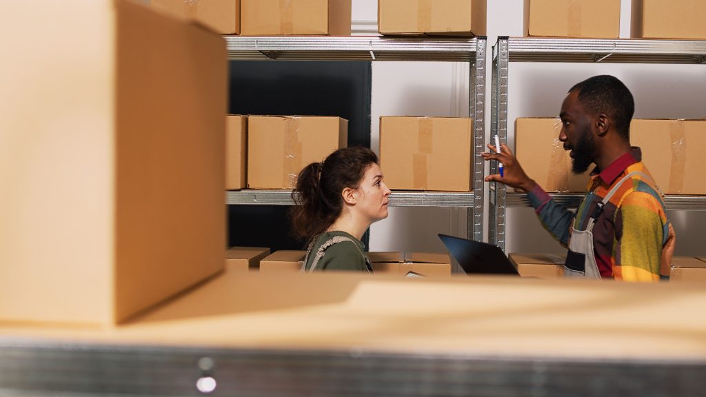 Diverse people reviewing supply chain in storage room discussing long-span vs. drive-in racking