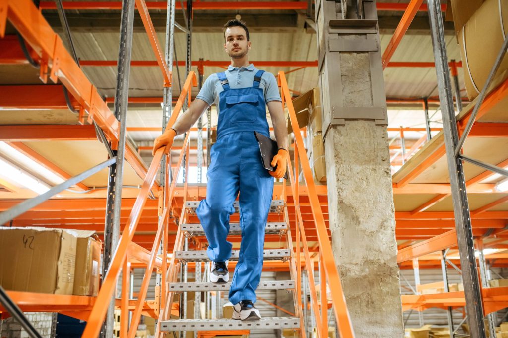 A warehouse worker walking down the stairs of a structural mezzanine floor design structure in a retail warehouse