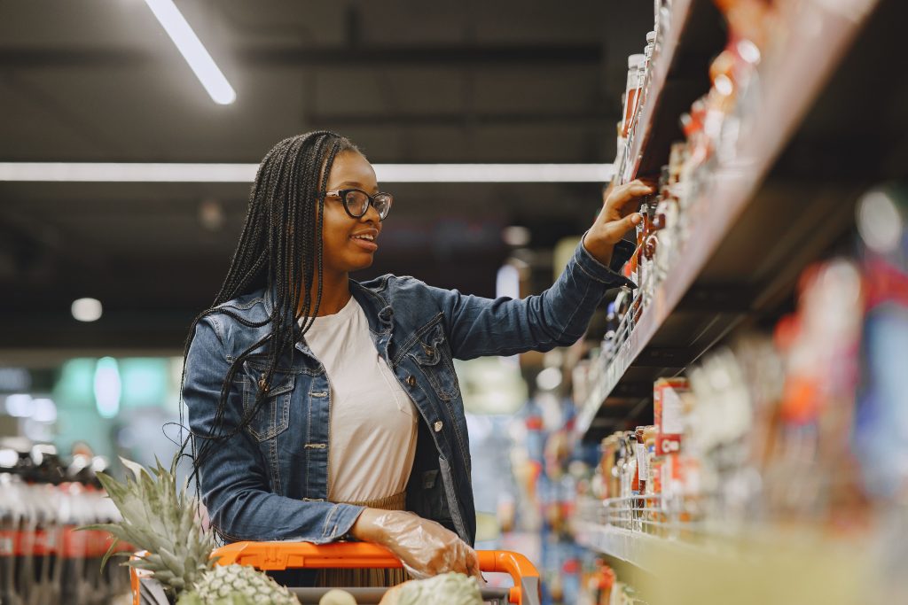 A young female picking items in a shop from gondola shelving Cape Town
