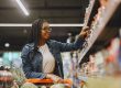 A young female picking items in a shop from gondola shelving Cape Town