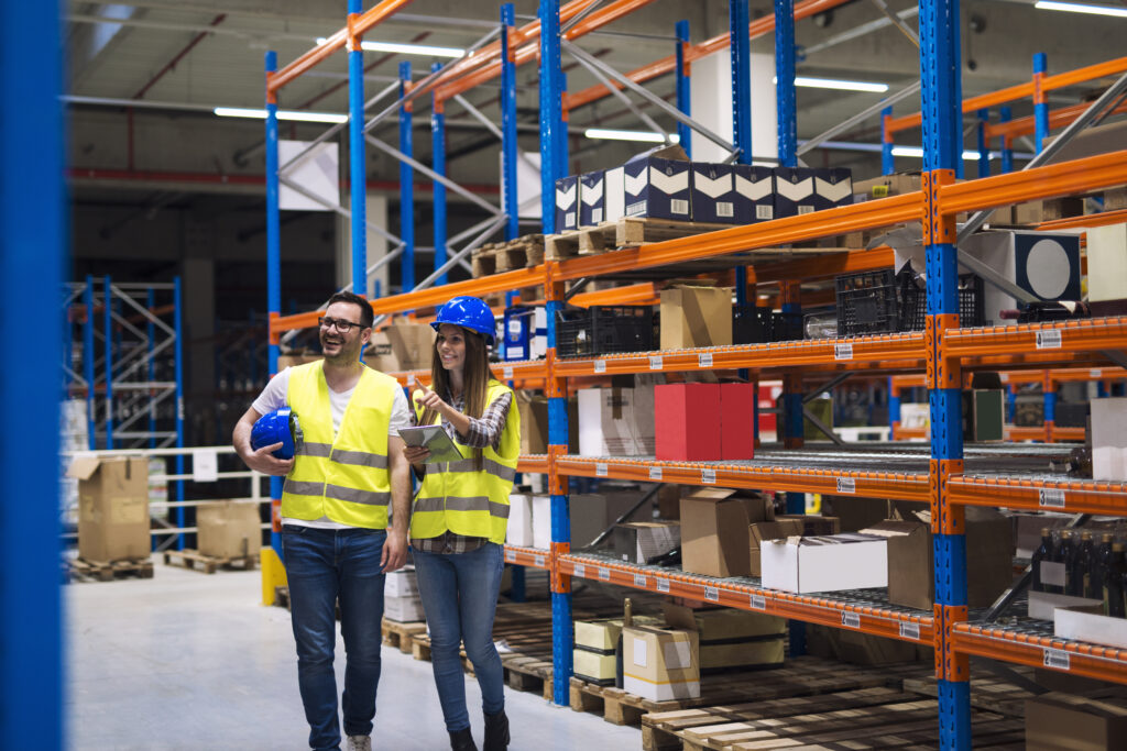 Warehouse team member pointing out stock on racking shelves to a colleague.