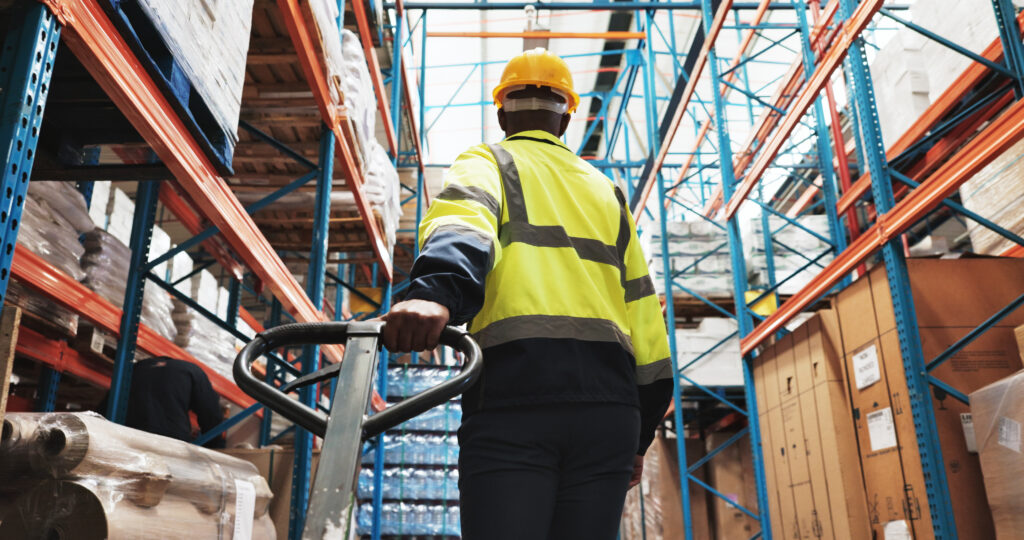 Warehouse worker pulling a pallet truck through selective pallet racking aisle